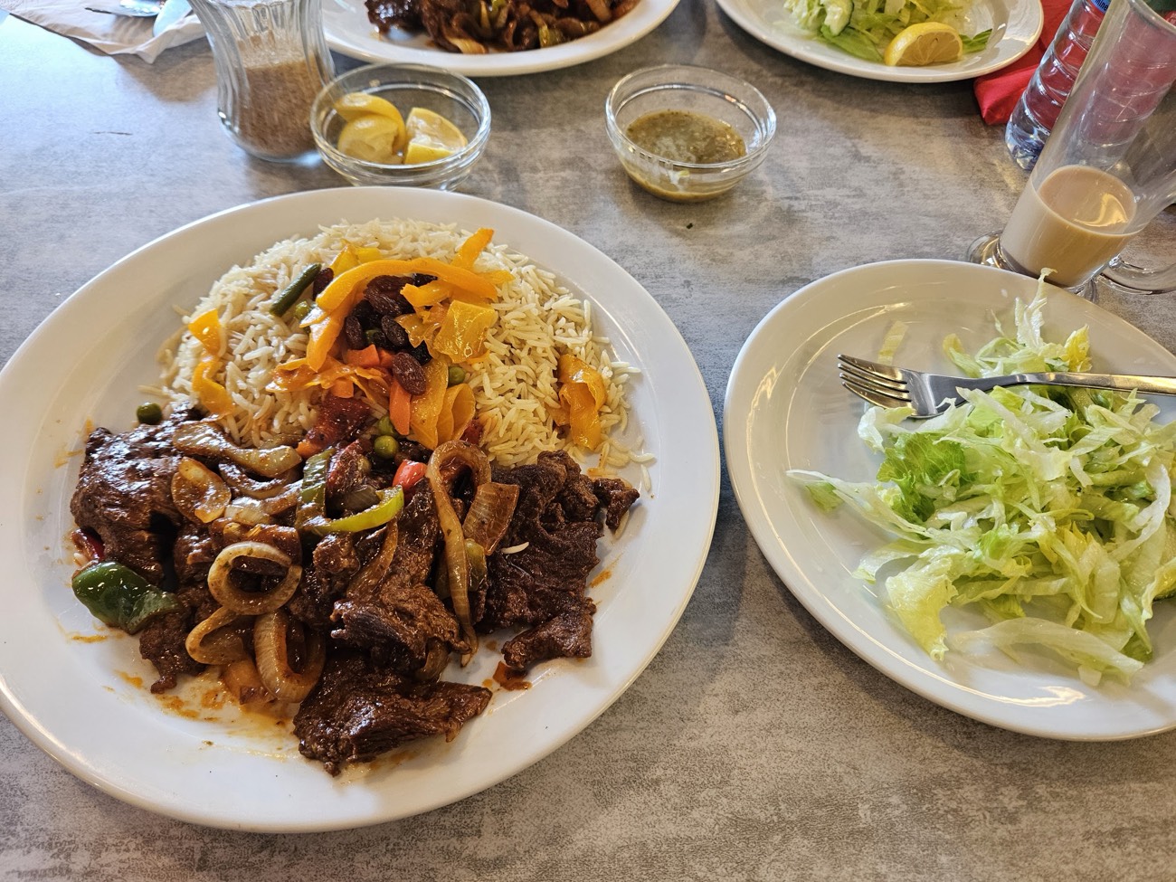 Beef suqaar with vegetable rice, fresh salad and a glass of Somali spiced tea on the table at Nafsoor