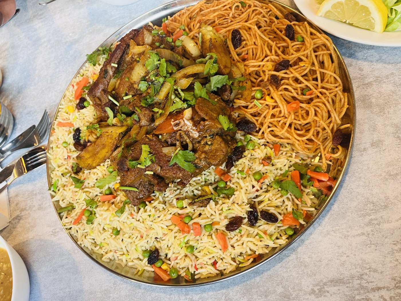 A Somali federation platter at Nafsoor — tender lamb over basmati rice and spiced spaghetti with raisins, peas and carrots